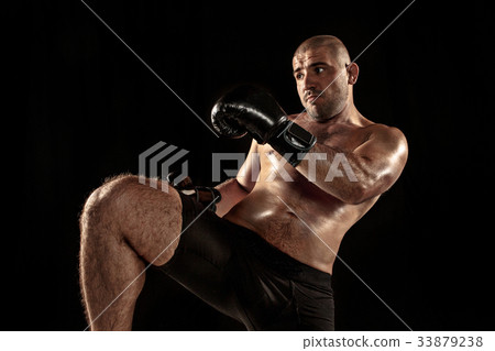 The young man kickboxing on black 33879238
