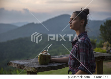 Hipster young girl with coconut enjoying sunset 33884145