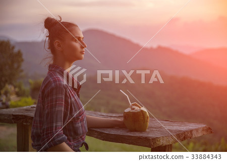 Hipster young girl with coconut enjoying sunset 33884343