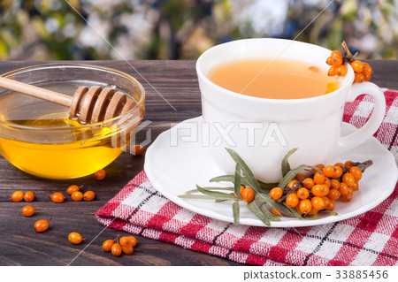 Tea of sea-buckthorn berries with honey on wooden Tea of sea-buckthorn berries with honey on wooden 33885456