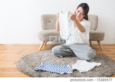 Pregnant woman looking at baby clothes 33889477