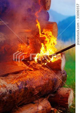 setting big bonfire made of logs on fire with 33890357