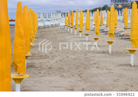 Closed umbrellas and deckchairs on the empty beach Closed umbrellas and deckchairs on the empty beach 33896922