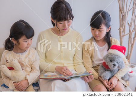 讀聖誕節書，父母和孩子的母親和女兒坐沙發，愉快的家庭或者家庭，家庭坐沙發 33902141