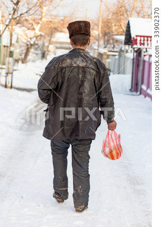 Homeless man is walking on the road in winter 33902370