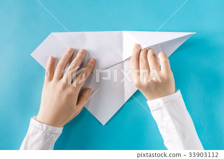 Person's hands folding a paper airplane 33903112