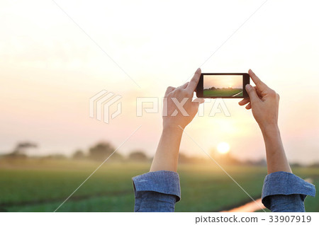 Woman taking photo in sunset, relax time in rural Woman taking photo in sunset, relax time in rural 33907919