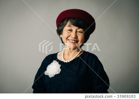 Senior lady putting on a beret 33909103