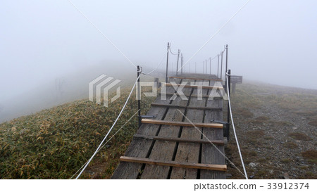 Wooden path at the top of the misty Kenzan peak 33912374