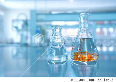 orange fluid in water in flask glassware 33913608