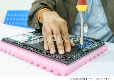 Repairman disassembling laptop motherboard.  33915142