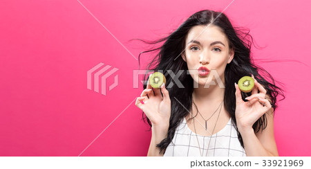 Happy young woman holding kiwis  33921969