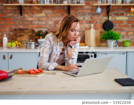 Cheerful woman cooking on modern kitchen Cheerful woman cooking on modern kitchen 33922836