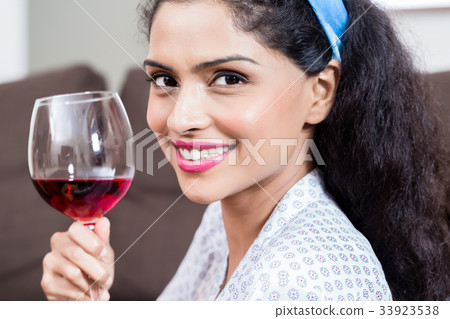 Beautiful young woman drinking red wine at home Beautiful young woman drinking red wine at home 33923538