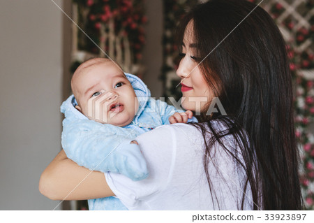 Loving Asian Mother Holding Baby Son At Home 33923897