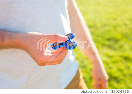 Close up of man playing with a blue hand spinner 33924816