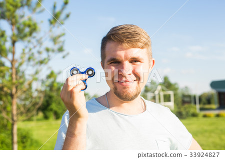 Young man holding and playing with fidget spinner 33924827
