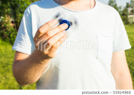 Close up of man playing with a blue hand spinner 33924968