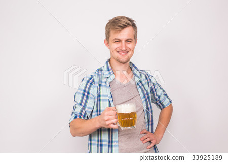 Cheerful young man holding a beer mug full of beer Cheerful young man holding a beer mug full of beer 33925189