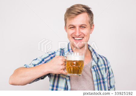 Cheerful young man holding a beer mug full of beer 33925192