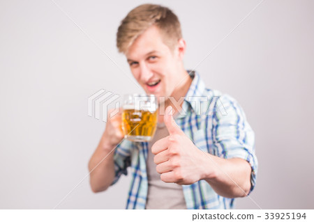 Happy young man holding beer mug and showing 33925194