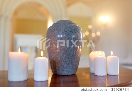 cremation urn and candles burning in church 33926784