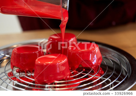 jug pouring glaze to cakes at pastry shop 33926966