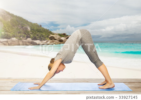 woman doing yoga dog pose on beach 33927145