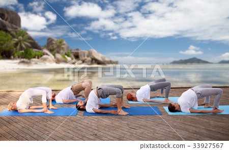 group of people making yoga exercises over beach 33927567
