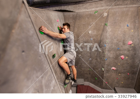 young man exercising at indoor climbing gym young man exercising at indoor climbing gym 33927946
