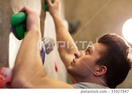 young man exercising at indoor climbing gym wall young man exercising at indoor climbing gym wall 33927947