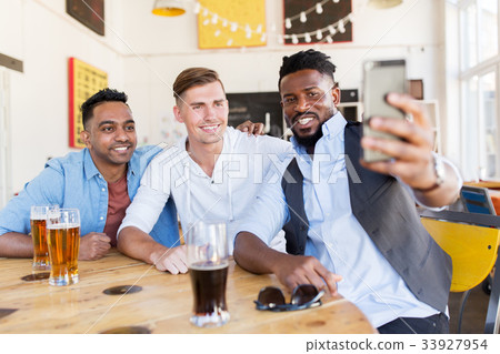 friends taking selfie and drinking beer at bar 33927954