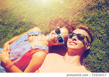 happy teenage couple lying on grass at summer 33928417