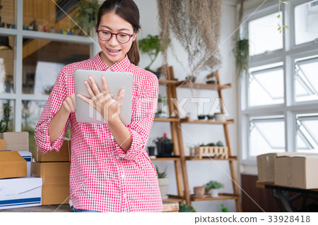 start up small business owner working with digital tablet at workplace. freelance woman entrepreneur SME seller check product order to prepare for delivery to customers. Online selling, internet marketing, e-commerce, shipping concept 33928418