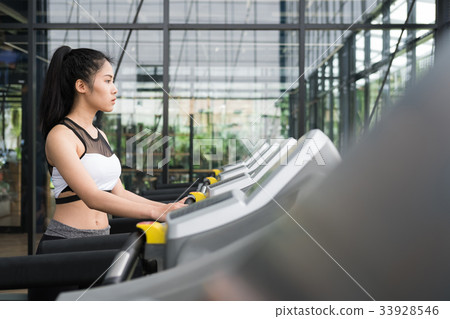 young woman execute exercise in fitness center. female athlete walking on treadmill in gym. sporty girl working out in health club. 33928546