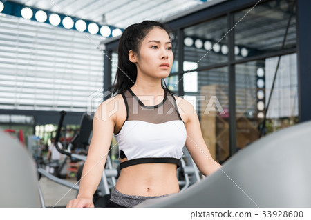young woman execute exercise in fitness center. female athlete walking on treadmill in gym. sporty girl working out in health club. 33928600