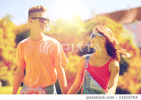 happy teenage couple walking at summer park 33928764