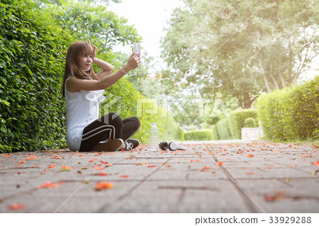 asian woman with headphones. young female holding mobile smart phone and take selfie photo. a pretty girl in public park 33929288