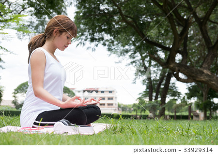 Yoga outdoors in public park. Asian woman sits in lotus position. Young female with zen gesturing. healthy lifestyle and relaxation concept 33929314