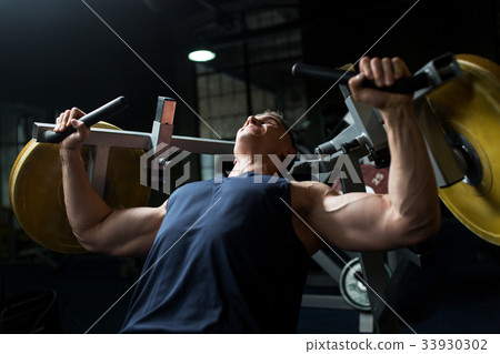 man doing chest press on exercise machine in gym 33930302