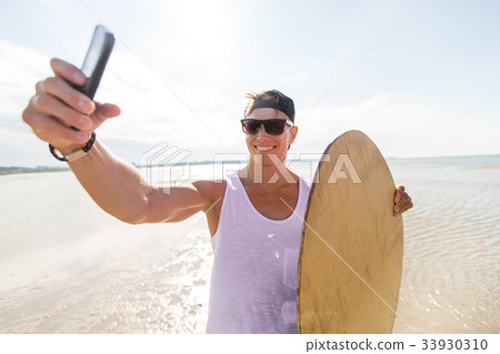 happy young man with skimboard on summer beach 33930310