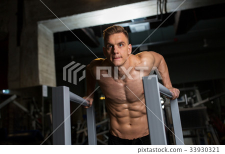 man doing triceps dip on parallel bars in gym man doing triceps dip on parallel bars in gym 33930321