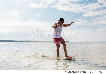 young man riding on skimboard on summer beach 33930762