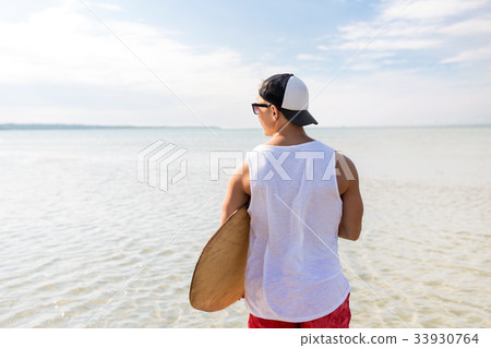 happy young man with skimboard on summer beach 33930764