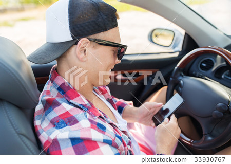happy young man with smartphone in convertible car happy young man with smartphone in convertible car 33930767