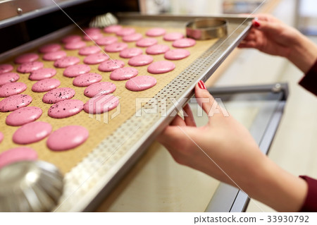 chef with macarons on oven tray at confectionery 33930792