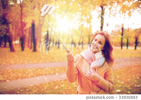 woman taking selfie by smartphone in autumn park 33930883