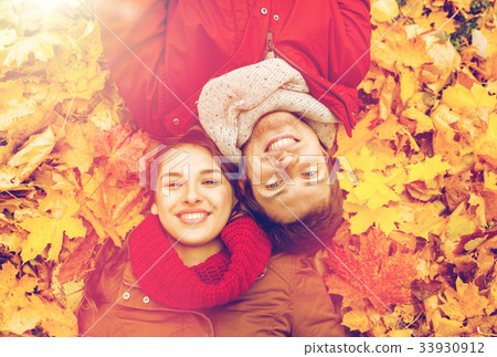 close up of smiling couple lying on autumn leaves close up of smiling couple lying on autumn leaves 33930912