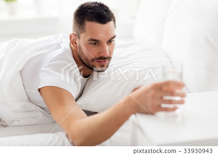 man in bed with glass of water at home man in bed with glass of water at home 33930943
