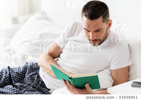 man reading book in bed at home man reading book in bed at home 33930951